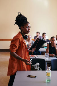 Confident young student holding digital tablet in classroom