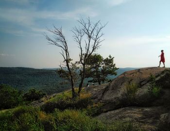 Woman standing on rock against sky