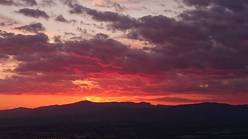Scenic view of dramatic sky over silhouette landscape