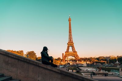 Woman sitting against eiffel tower in city