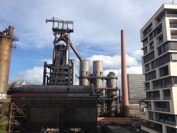 Low angle view of crane against cloudy sky