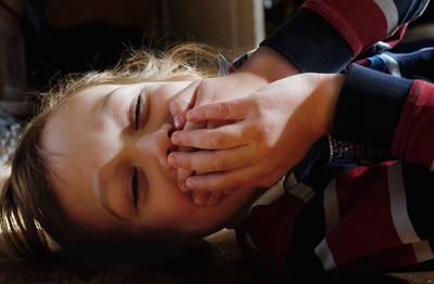 Close-up of boy covering mouth while lying at home