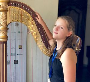 Thoughtful teenage girl with harp at home