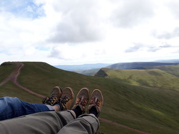 Low section of two people against view of pen y fan mountain, wales. 