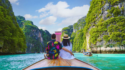 Rear view of man sitting on boat in lake