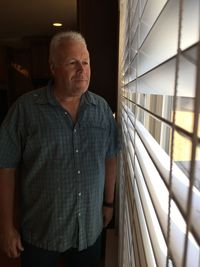 Senior man looking through window at home