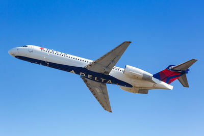 Low angle view of airplane against clear blue sky