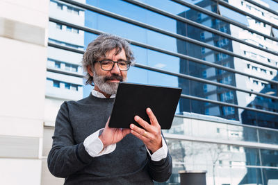 Young man using digital tablet while standing in office