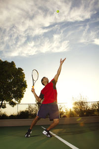 Man playing tennis at field against sky