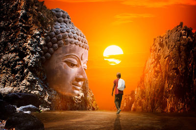 Digital composite image of statue against orange sky