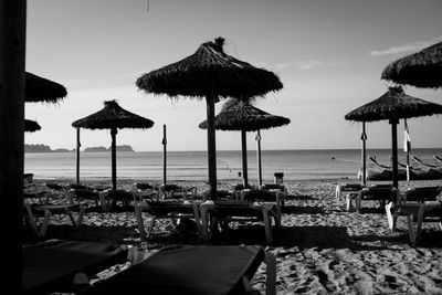 Lounge chairs and parasols at beach against sky