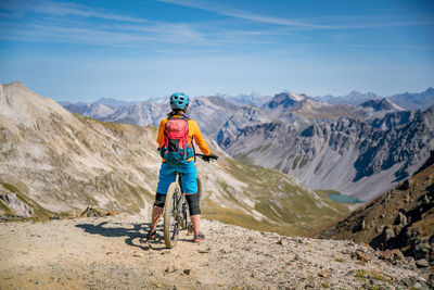 Woman on mountain bike enjoying panoramic view at alpine landscape, arosa, swiss alps, switzerland.