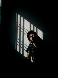 Young man sitting in shadow of window