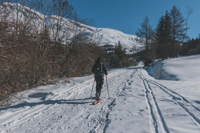An unrecognizable male hiker wearing snowshoes walking in the french alps on a cold winter day