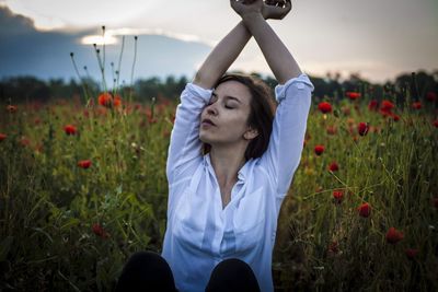 Portrait of young woman with flowers in field