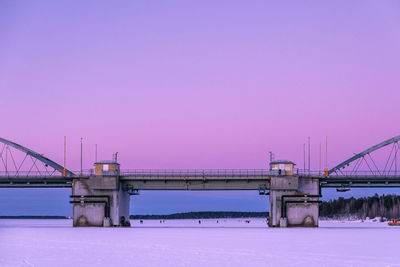 Bridge over water against clear sky during winter