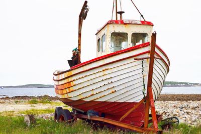 Boat moored on beach against clear sky