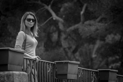 Portrait of woman standing against railing