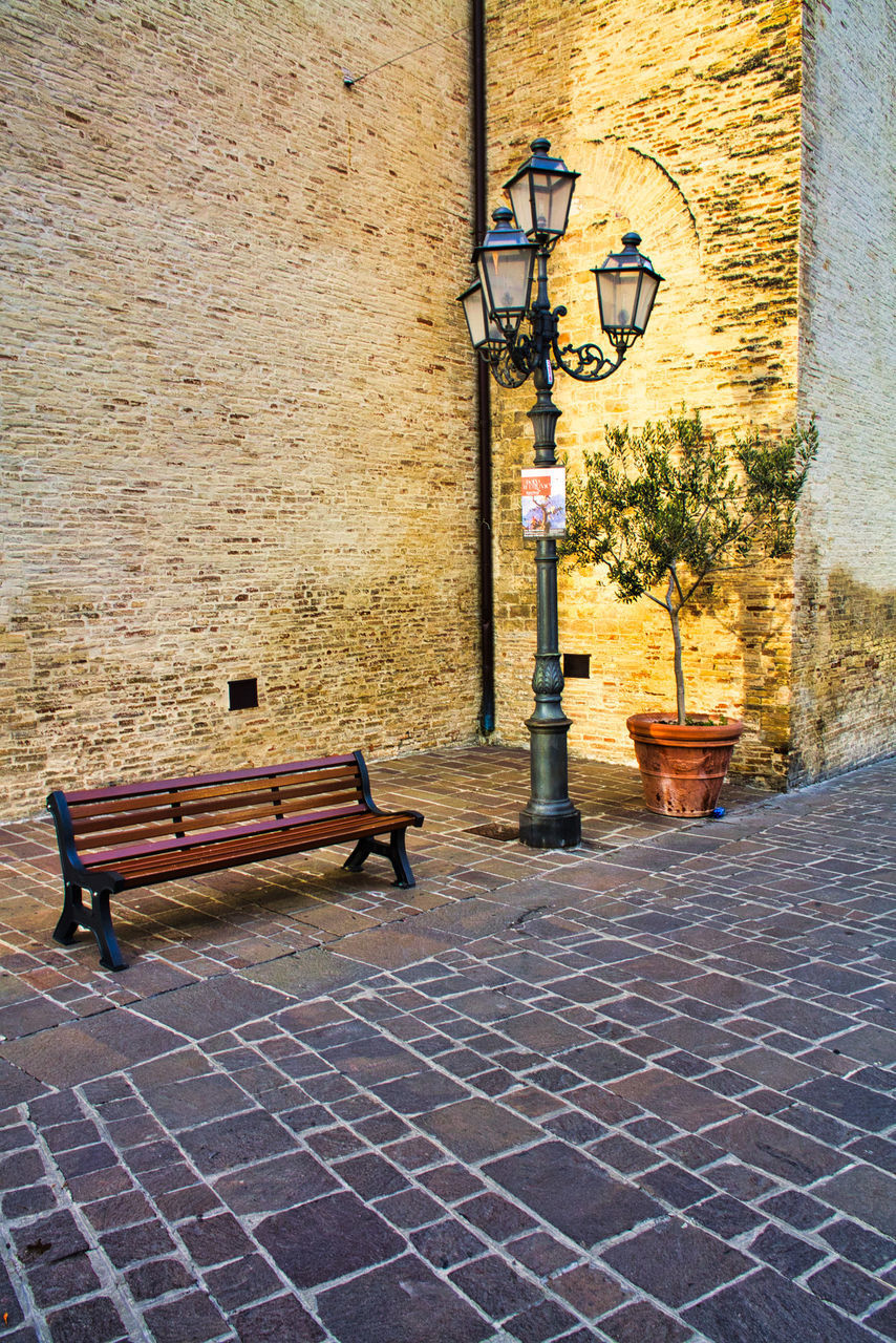 EMPTY BENCH ON STREET BY WALL