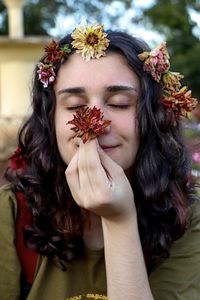 Girl with flowers in the hair and hands, smiling and smelling