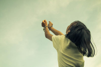 Girl handcuffs against cloudy sky