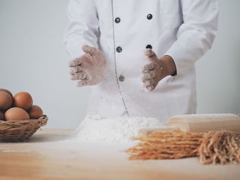 Midsection of chef preparing food on table against white background