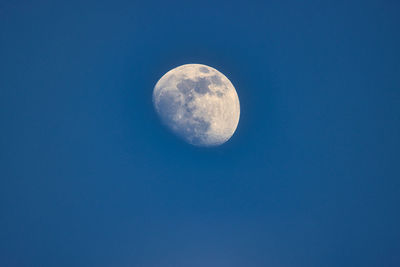 Low angle view of moon against clear blue sky