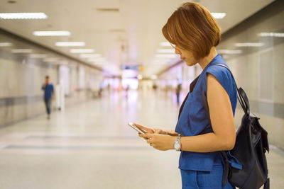 Side view of woman standing in underground walkway