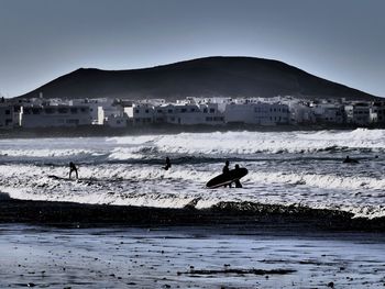 Silhouette man surfing in sea against clear sky