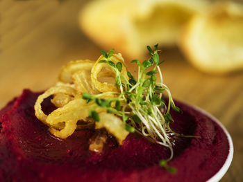 Close-up of beetroot hummus with sprouts in bowl on cutting board