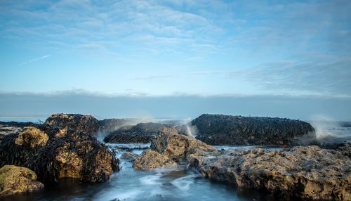 Rocks in sea against sky