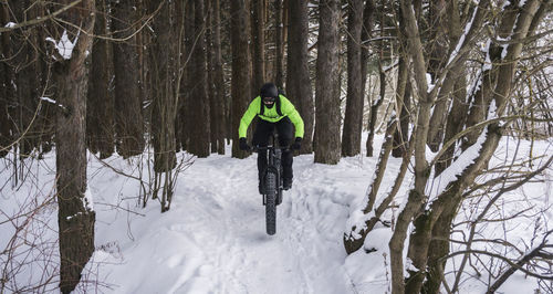 Full length of man cycling on snow covered land