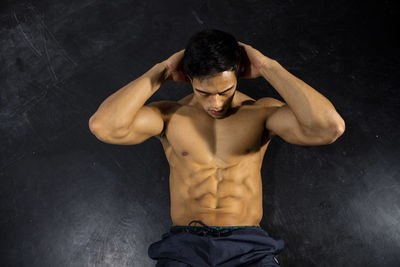 Shirtless muscular man exercising against wall