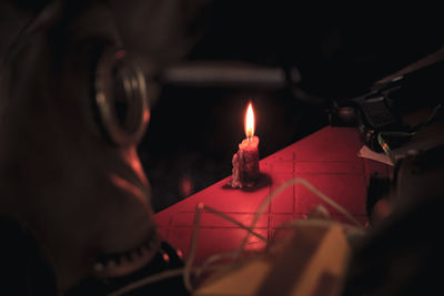 High angle view of candle burning on table in darkroom