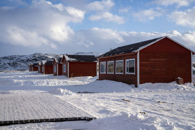 White house on snow covered field against sky