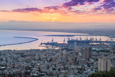 High angle view of buildings by sea against sky during sunset