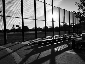 Shadow of trees by fence against sky