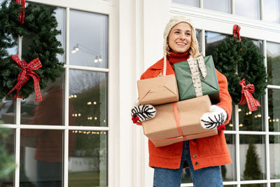 Woman with christmas presents walking at home. female holding winter holidays gifts