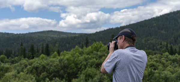 Rear view of man standing on mountain against sky