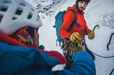 Two male alpine ice climbers sort and exchange ice and rock gear