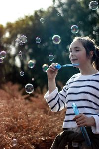 Close-up of smiling girl playing with bubbles