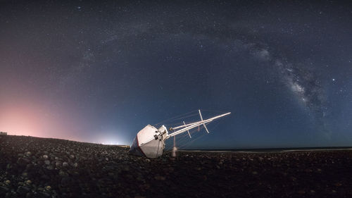 Wind turbines on field against sky at night