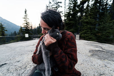 Portrait of woman holding her cat and giving it love in outdoor space 