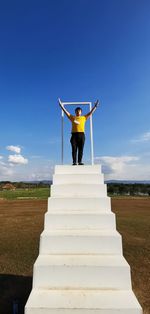 Woman standing on staircase in field against sky