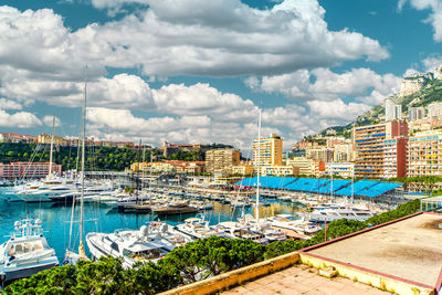 Harbor by buildings against cloudy sky