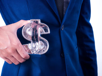 Close-up of hand holding glass against blue background