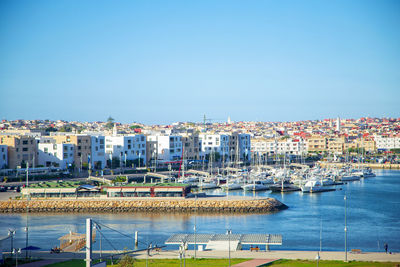 Boats moored in harbor against clear blue sky