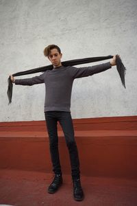 Portrait of young man standing against wall