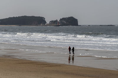 People on beach against clear sky