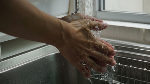 Close-up of hand touching water in bathroom